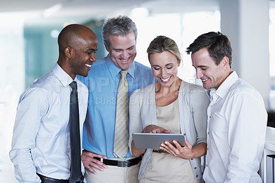 Buy stock photo Shot of a group of coworkers looking at a digital tablet while standing in an office