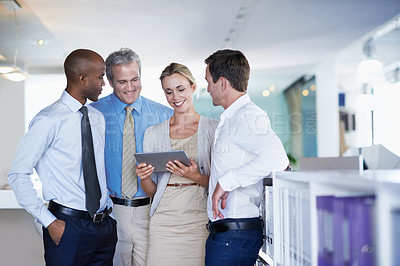 Buy stock photo Cropped shot of a group of coworkers looking at a digital tablet while standing in an office