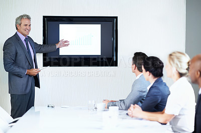 Buy stock photo Shot of a mature businessman giving a video presentation to colleagues in a boardroom