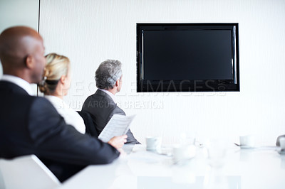 Buy stock photo Shot of a diverse group of businesspeople sitting around a boardroom table looking at a blank monitor