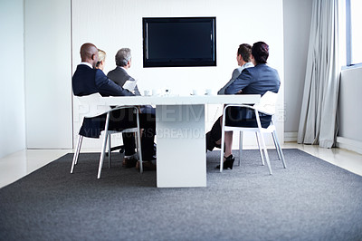 Buy stock photo Full length shot of a group of businesspeople sitting around a boardroom table looking at a blank monitor