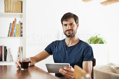 Buy stock photo Portrait of a handsome young man using his tablet while sitting at home