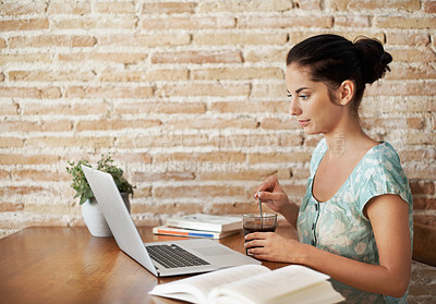 Buy stock photo A beautiful young woman doing some research using her laptop and text book