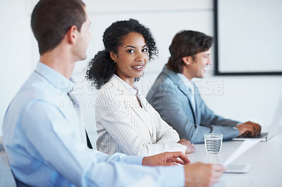 Buy stock photo Portrait of a young businesswoman sitting beside her coworkers in a board room