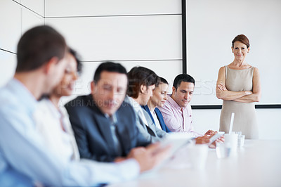 Buy stock photo A female manager standing by her coworkers in a board room