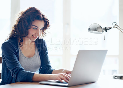 Buy stock photo A pretty young woman using her laptop at home