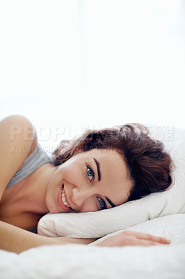Buy stock photo A pretty young woman lying comfortably in her bed smiling at you - copyspace