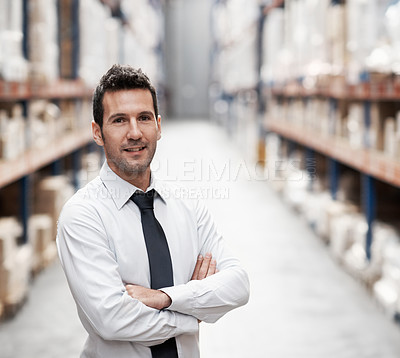 Buy stock photo Handsome warehouse manager standing in a warehouse with his arms folded