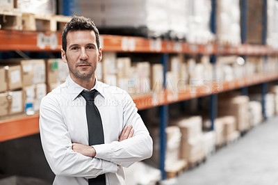 Buy stock photo Handsome warehouse manager standing in a warehouse with his arms folded