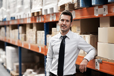 Buy stock photo Relaxed warehouse manager standing in a warehouse surrounded by boxes