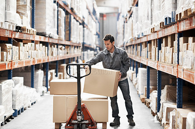 Buy stock photo A young man using a pallet truck to transport boxes in a warehouse