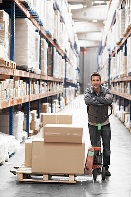 Buy stock photo Portrait of a young man using a pallet truck to move boxes in a warehouse