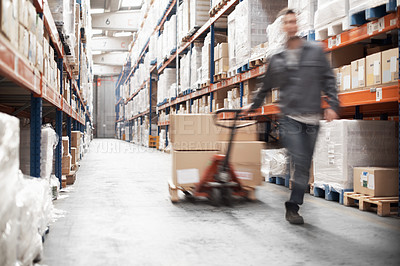 Buy stock photo A young man using a pallet truck to move stock in a storehouse