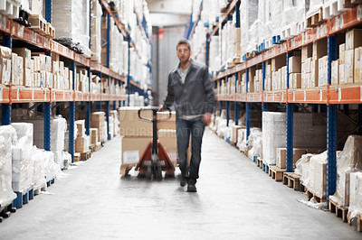 Buy stock photo A young man in a storehouse transporting inventory using a pallet truck