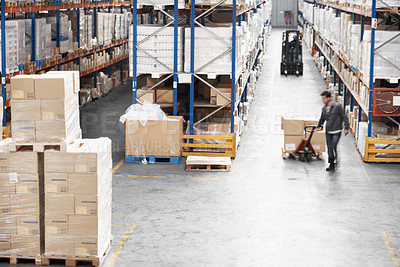 Buy stock photo A young man moving boxes in a warehouse using a pallet truck