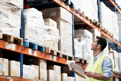 Buy stock photo A young man doing stock take in a warehouse