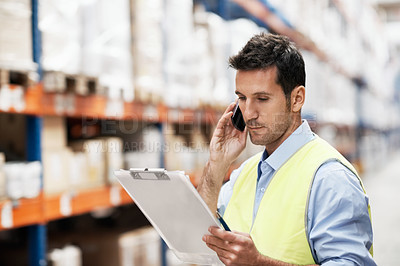 Buy stock photo A young man in a storehouse taking orders on his cellphone