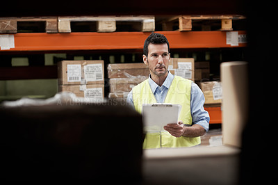 Buy stock photo A young man counting supplies in a warehouse