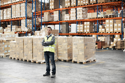 Buy stock photo Portrait of a young man standing with his arms folded in a warehouse