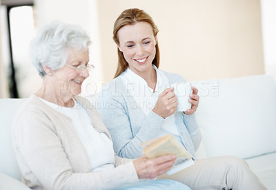 Buy stock photo Reading book, tea and senior mother with women bonding, relax together and connection in home. Novel, elderly parent and adult daughter with drink in living room, story conversation and happy family
