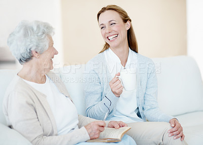 Buy stock photo Bonding, smile and old woman in home with daughter, friendly chat or happiness in lounge. Retirement, senior mother or family in house with book, connection or joke reaction in loving relationship.