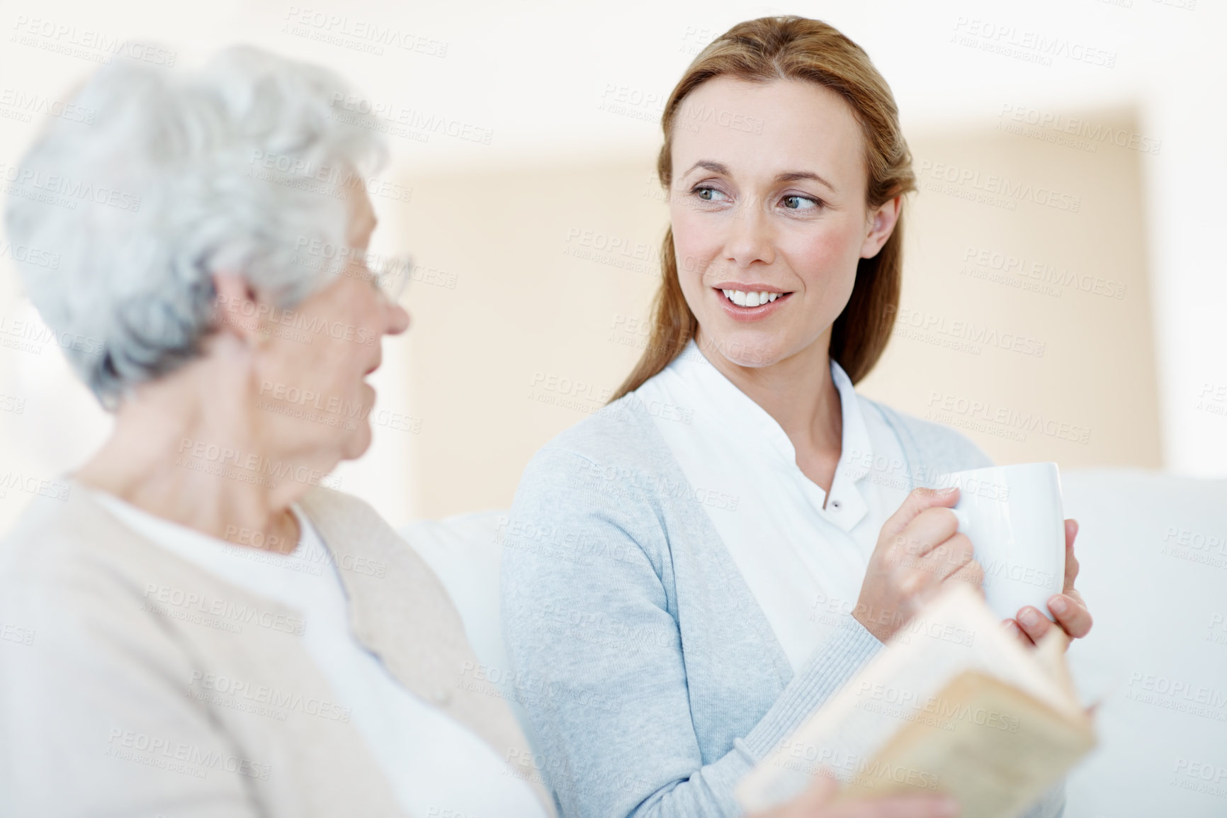 Buy stock photo Book, coffee and mother with old woman for care, bonding together and conversation in home. Novel, elderly parent and adult daughter with drink in living room, gossip story and happy family with love