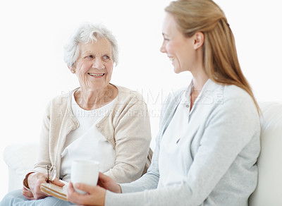 Buy stock photo Bonding, senior mother and women with coffee in home, smile and connection together on weekend. Elderly parent, adult daughter and love in living room with drink, book and gossip with happy family