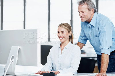 Buy stock photo A young businesswoman working on her computer as her boss looks on