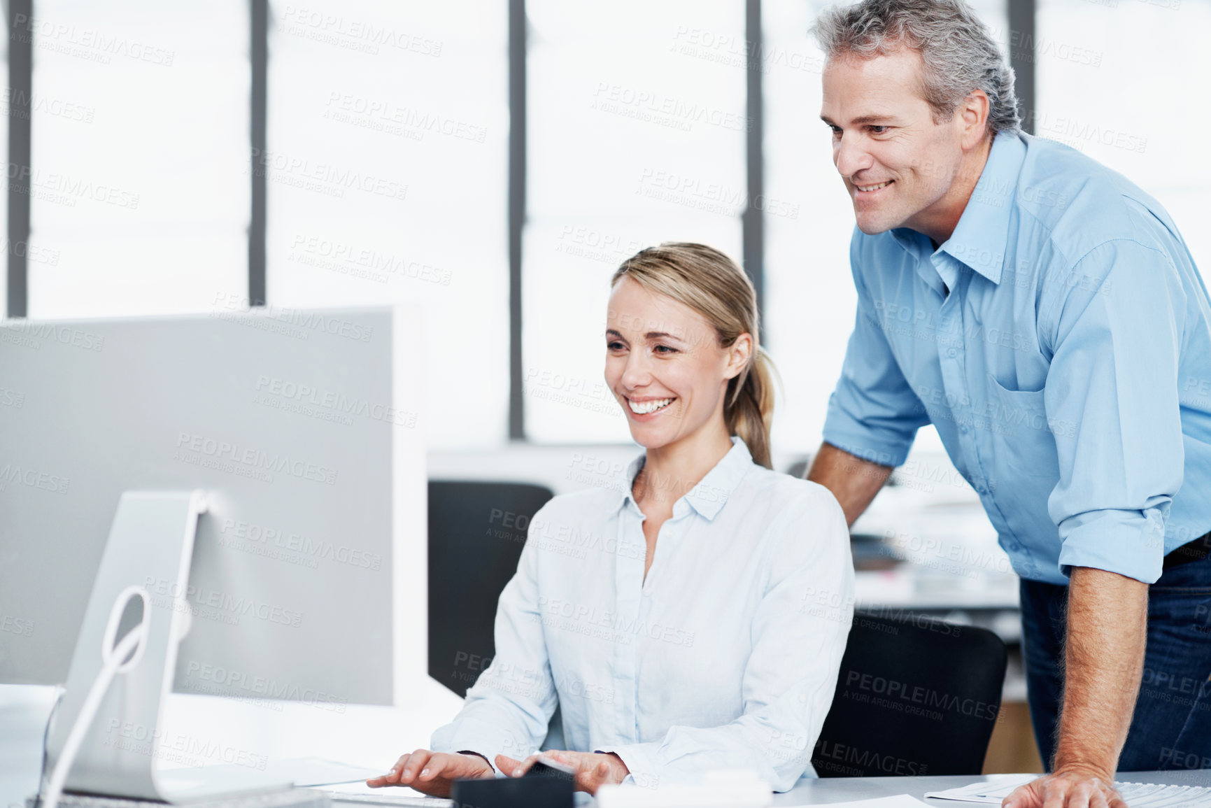 Buy stock photo A young businesswoman working on her computer as her boss looks on