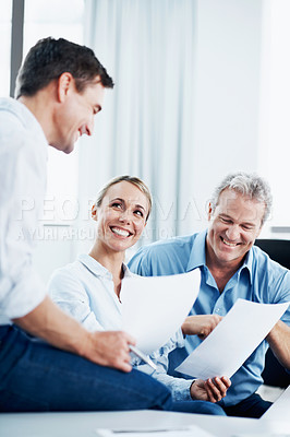 Buy stock photo Three colleagues having a discussion over some paperwork in the office