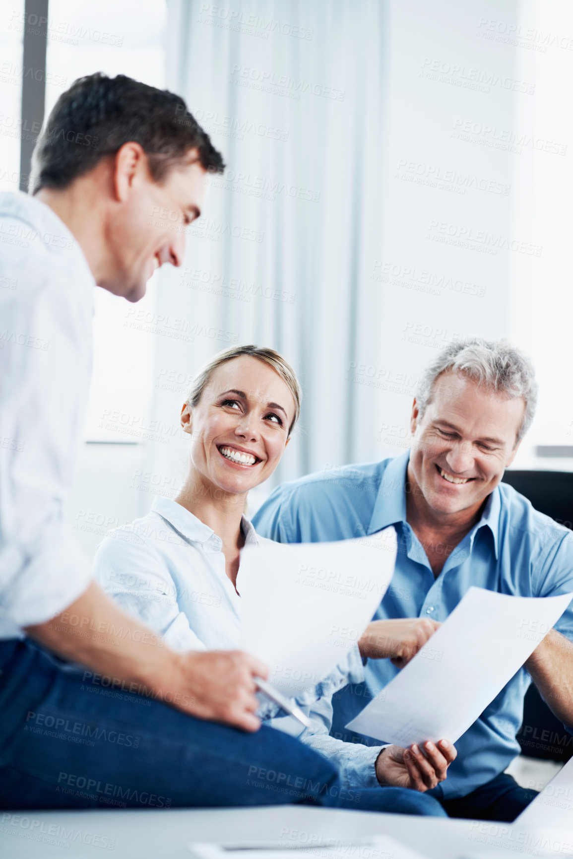Buy stock photo Three colleagues having a discussion over some paperwork in the office