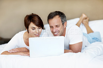Buy stock photo Reading, laptop and couple together on bed with love, care and bonding with comfort and web in home. Happy man, woman and tech in bedroom with internet connection, streaming online and subscription