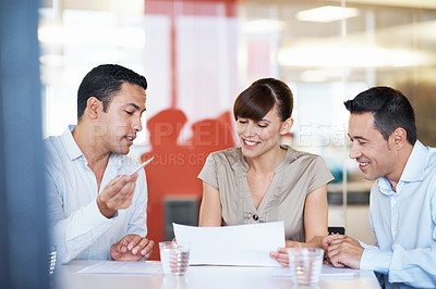 Buy stock photo Shot of coworkers discussing paperwork around a table in an office