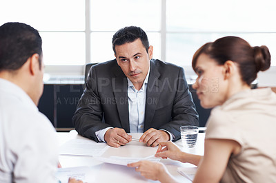 Buy stock photo Shot of coworkers discussing paperwork around a table in an office
