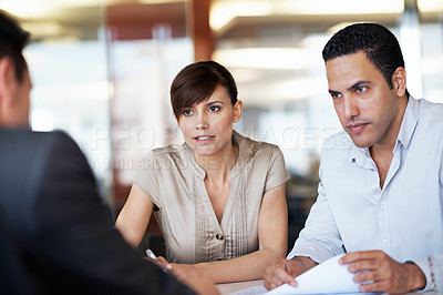 Buy stock photo Shot of coworkers discussing paperwork around a table in an office