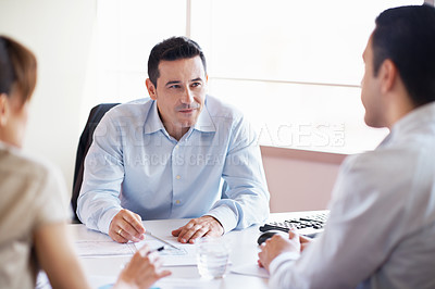 Buy stock photo Shot of coworkers discussing paperwork around a table in an office