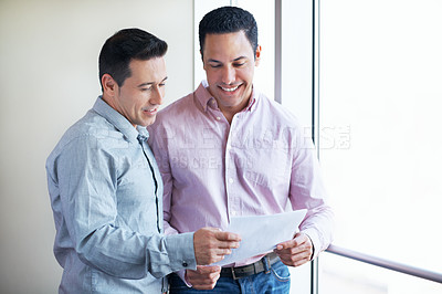 Buy stock photo Shot of two colleagues discussing paperwork while standing in an office