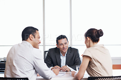 Buy stock photo Shot of coworkers discussing paperwork around a table in an office