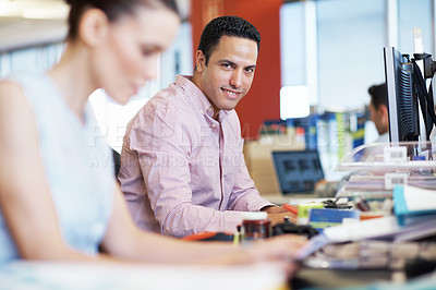 Buy stock photo Portrait of a young businessman at his office desk with a female coworker in the foreground