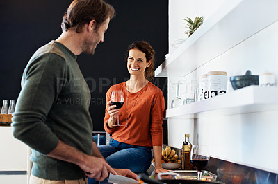 Buy stock photo Shot of a mature couple drinking wine while preparing dinner in their kitchen