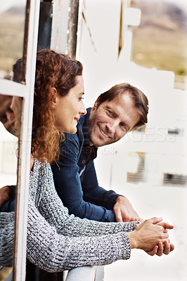 Buy stock photo Shot of a mature couple leaning on their balcony railing looking outside