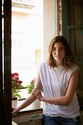 Buy stock photo Portrait of an attractive young woman standing by a window in her home