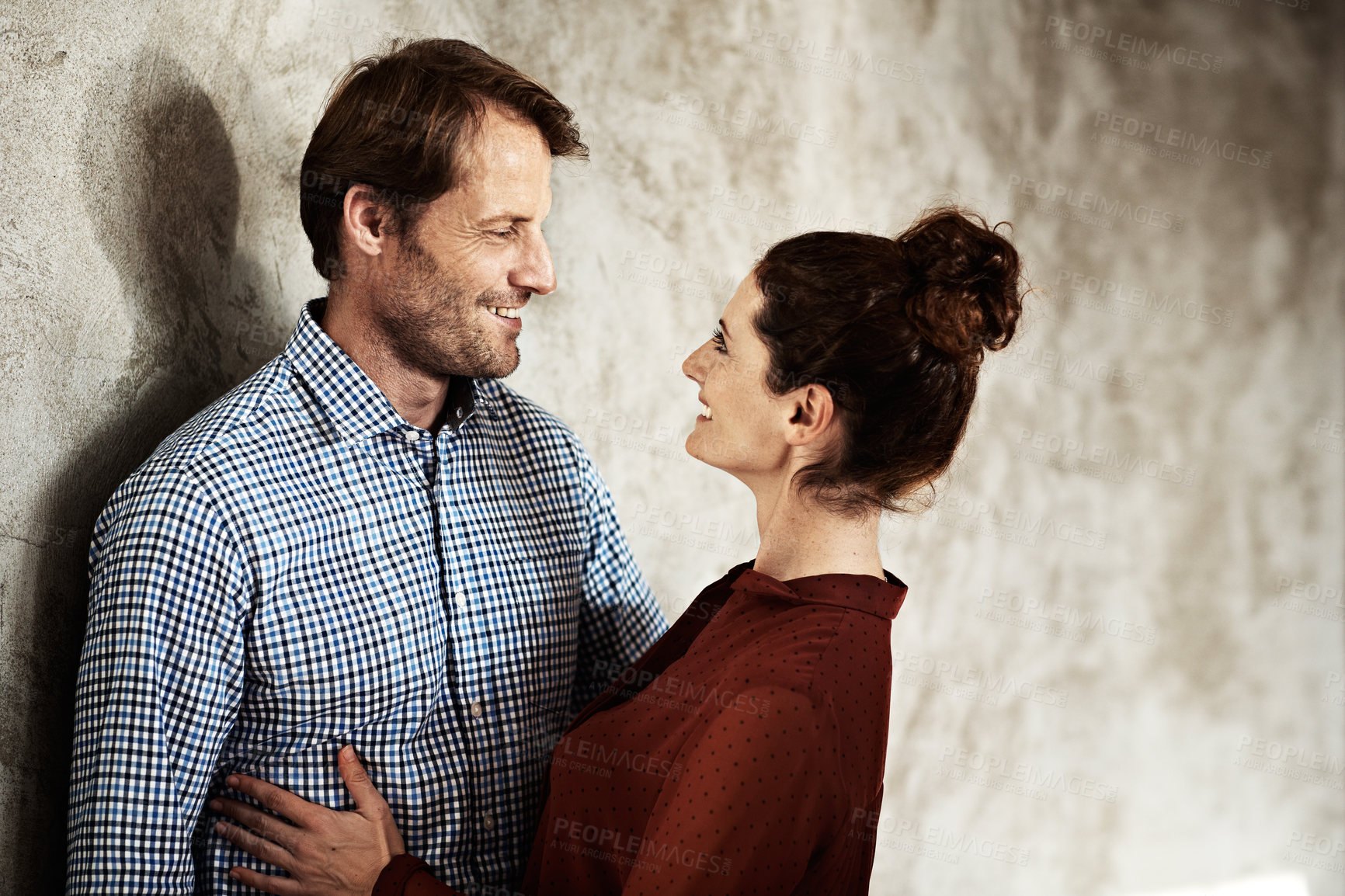 Buy stock photo Shot of an affectionate couple leaning against a wall
