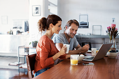 Buy stock photo Shot of a smiling couple using a laptop while eating breakfast