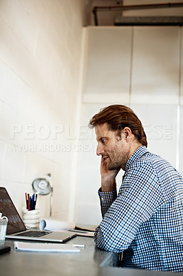 Buy stock photo Shot of a man talking on his phone while working on a laptop