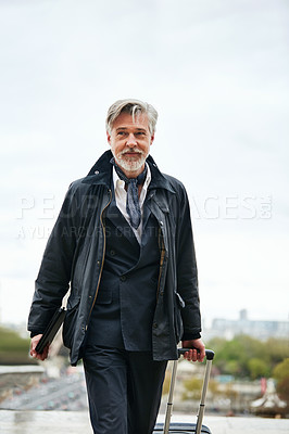 Buy stock photo Shot of a mature man pulling a suitcase while walking through the city