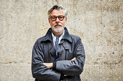 Buy stock photo Portrait of a handsome mature man standing with his arms crossed against a wall in the city