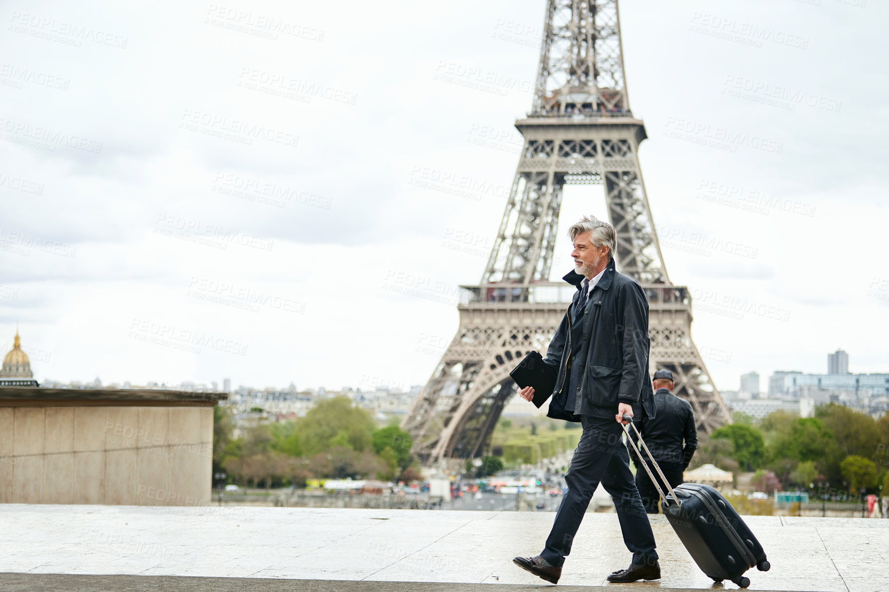 Buy stock photo Shot of a mature man walking with a suitcase in Paris with the Eiffel Tower in the background