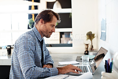 Buy stock photo Shot of a businessman working on a laptop at his desk in an office