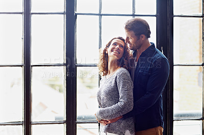Buy stock photo Shot of an affectionate mature couple hugging in front of a window at home